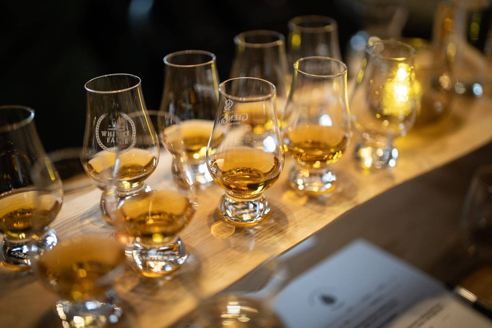 Provningsglas med whisky står på rad längs långbordet, med ett värmeljus mellan dem.